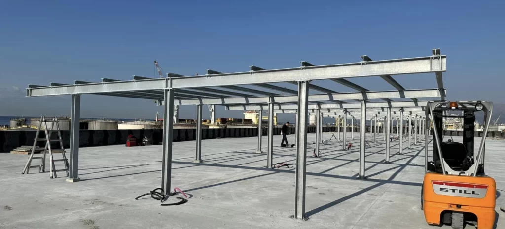 Installazione su tetto azienda AOC, porto di Genova, di tettoia in ferro per impianto fotovoltaico.